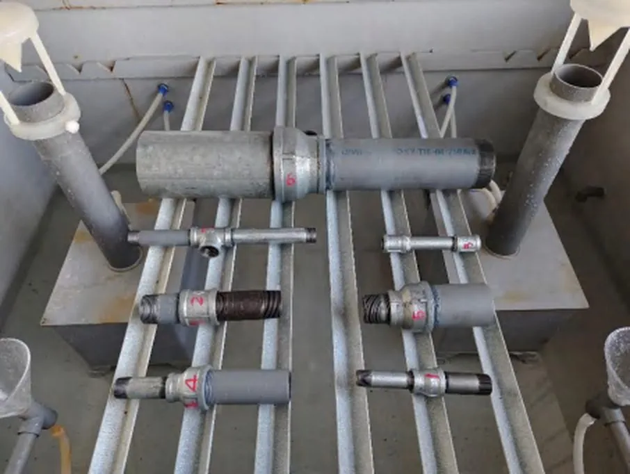 Rolled and cut-thread pipe nipple samples racked side by side inside the neutral salt-spray chamber